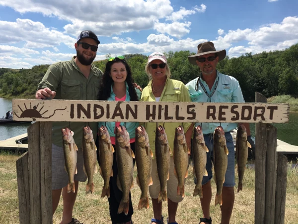 People standing in front of sign holding fish.